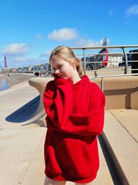 Young woman standing on red against sky