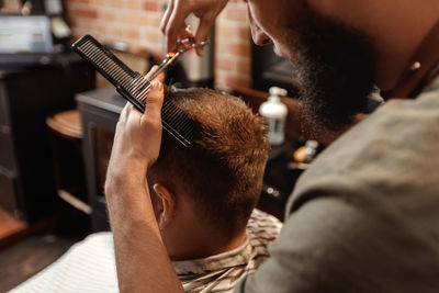 Barber trimming hair of customer