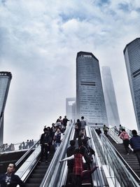 People on modern buildings in city against sky