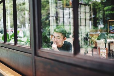 Portrait of man looking through glass window