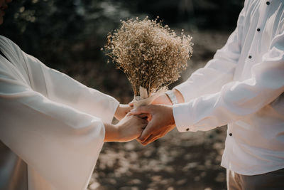 Two lover holding a dried flower with their hand to show their love and affection