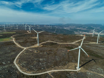 Wind turbines on field against sky