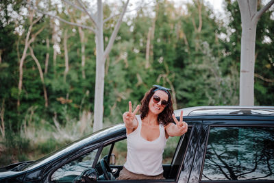 Young woman wearing sunglasses while sitting on car