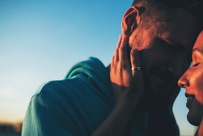 Close-up of couple embracing against blue sky