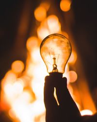 Close-up of hand holding illuminated light bulb