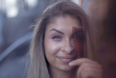 Close-up portrait of smiling beautiful woman holding film negative