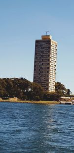 Building by sea against clear blue sky