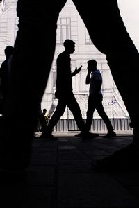 Silhouette people walking on footpath