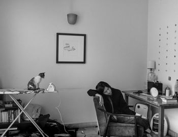 MAN SITTING WITH CAT ON FLOOR AT HOME