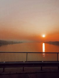 Bridge over sea against sky during sunset