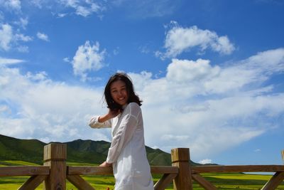 Portrait of smiling young woman standing against sky