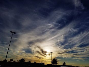 Low angle view of silhouette street light against dramatic sky