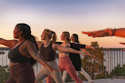 Female friends doing yoga on patio at sunset