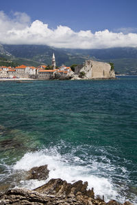 Scenic view of sea by buildings against sky