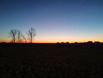 Scenic view of silhouette field against clear sky during sunset