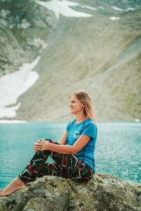 Woman sitting on rock by sea