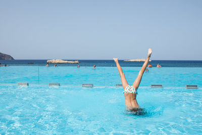 Low section of person in swimming pool against sea