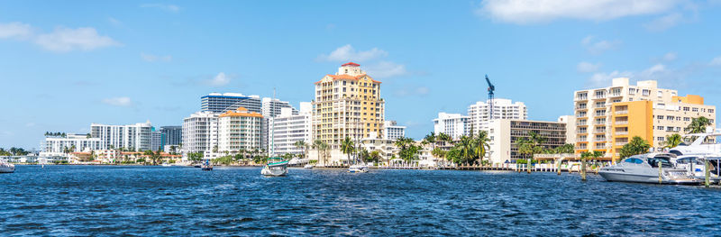 Buildings by sea against blue sky