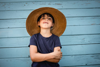 Portrait of funny child in straw hat with folded arms