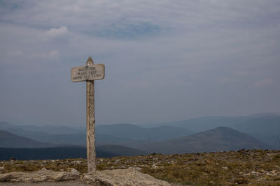 Road sign by mountains against sky