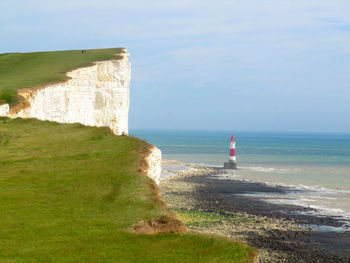 Scenic view of mountain cliff and sea against sky