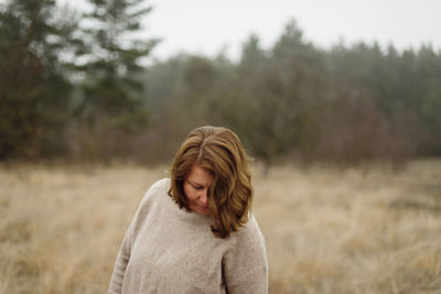 Woman standing by forest in foggy weather