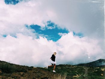 Woman walking on mountain against sky