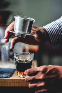 Close-up of hands preparing coffee on table