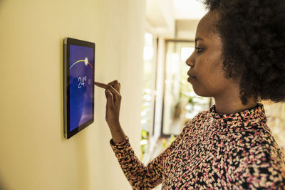 Afro woman using home automation device on wall