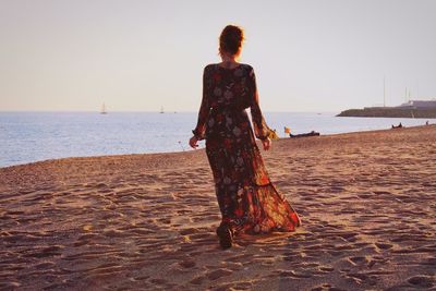 Rear view of woman on beach against sky