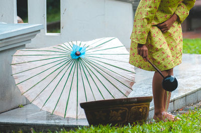 Low section of woman washing feet using bamboo dipper