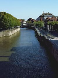 Canal in front of river against clear blue sky