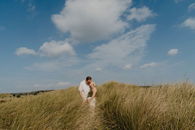 Rear view of woman standing on field against sky