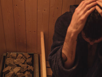 Young man wearing bathrobe relaxing in sauna