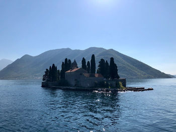 Scenic view of sea and mountains against clear blue sky