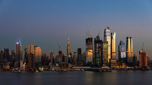 Illuminated modern buildings in city against sky