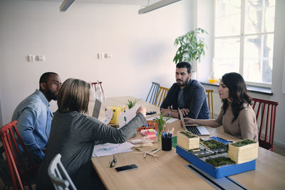 Male and female engineers sharing ideas while working on project at table in office