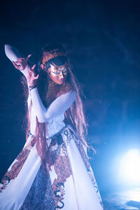 Woman wearing mask while dancing in dark