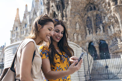 Happy young woman using smart phone in city