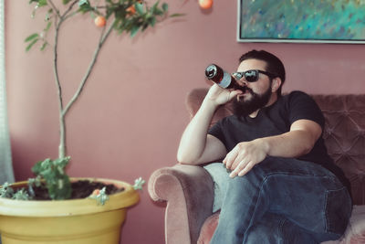 Portrait of young man sitting on potted plant