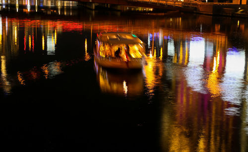 Reflection of illuminated boat in river at night