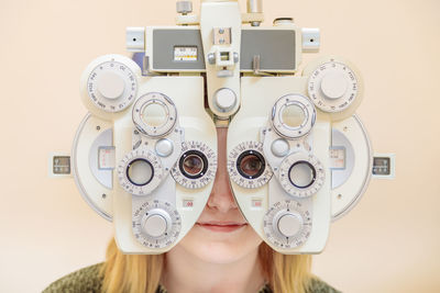 A male ophthalmologist checks a girl's eyesight using a phoropter. vision treatment