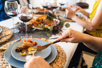 From above of crop unrecognizable people enjoying tasty dish while sitting at table during christmas holiday