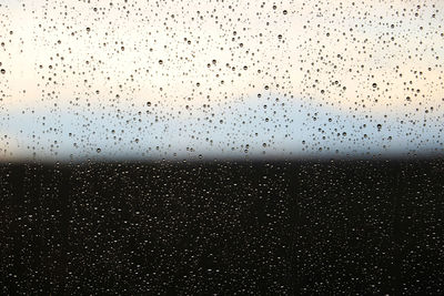 Raindrops on sky seen through wet windshield