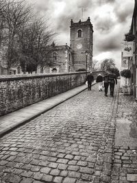 People walking on city street against sky