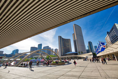 People on modern buildings in city against sky