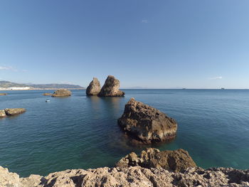 Scenic view of rocks in sea against blue sky