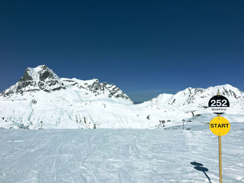 Scenic view of snow covered mountains against clear blue sky