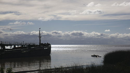 Sailboats moored on sea against sky