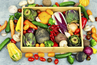 Colorful set of vegetables in a wooden box. pumpkin pepper cucumber tomato artichoke 